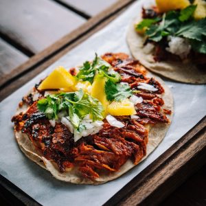 Vertical shot of al pastor tacos on wooden tray in Mexico Vertical shot of al pastor tacos on wooden tray in Mexico